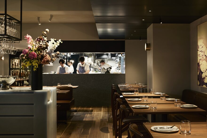 Interior of Nomad restaurant showing tables set and ready for dining patrons, with the open kitchen area visible in the background.