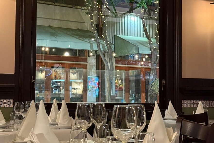Interior of The Summit Club restaurant showing tables set for service with a view out the window onto the street.