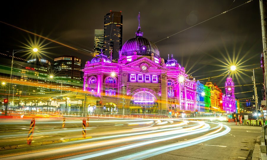 Flinders Street Station illuminated in rainbow colours at night.