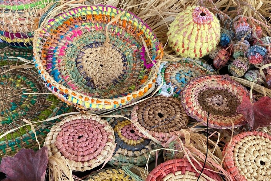 Coil-woven circles in pink and yellow tones.