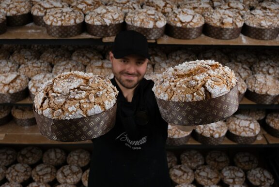 An employee at Brunetti's holding up two panettone festive cakes.