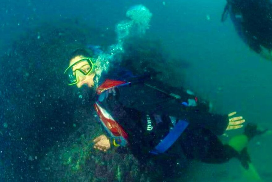 Iranian filmmaker Mozhgan Pazooki swimming underwater with diving equipment while wearing a hijab.