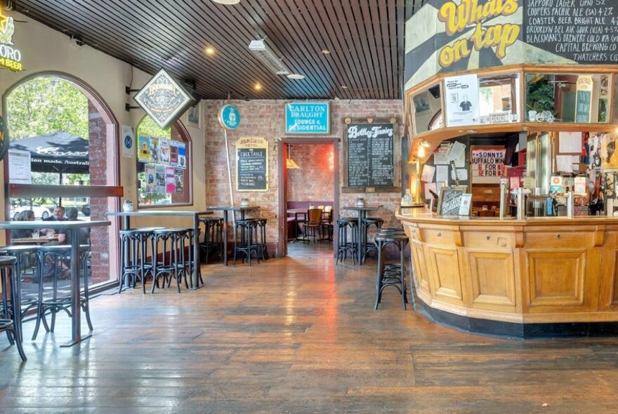 The timber bar area of the John Curtin Hotel with large arched windows showing the street outside. 