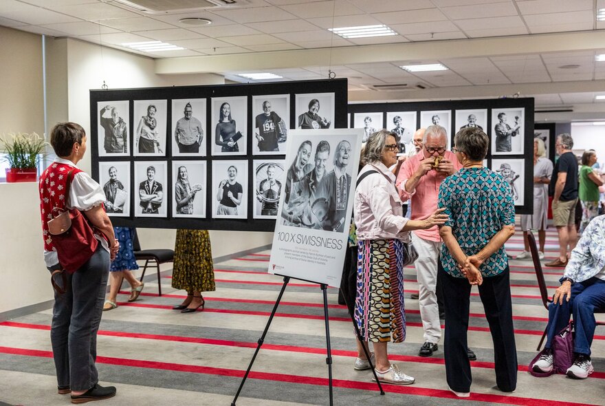 People in a gallery space looking at portraits displayed on boards.
