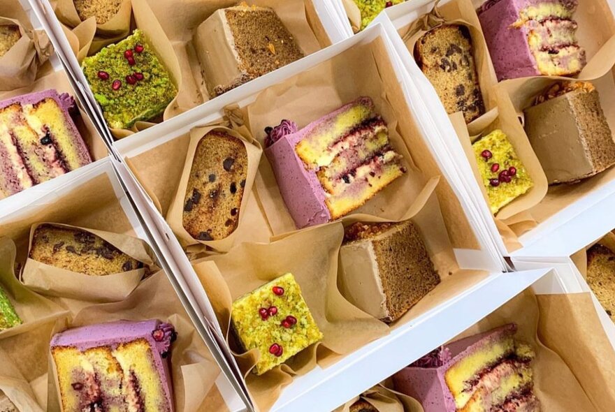 Boxed lunches with sandwiches and cakes in wrappers.