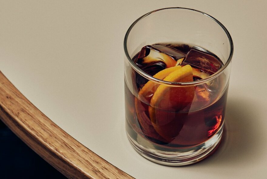 A drink with ice and lemon resting on a table.