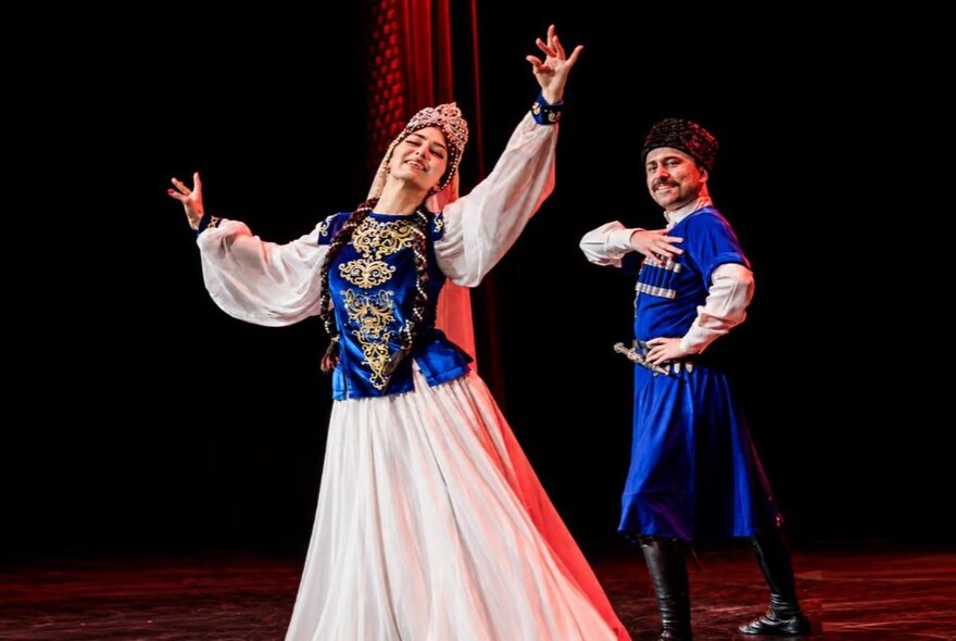 A Persian dance couple wearing traditional blue silk clothing.