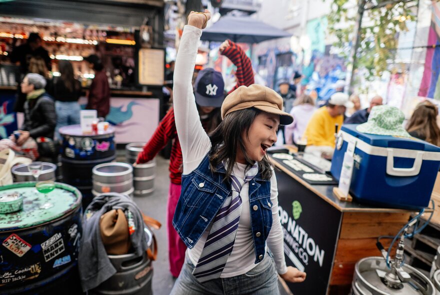 A young woman in a tie and denim vest, dancing.