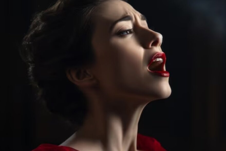 Closeup profile of a woman singing with an open mouth.