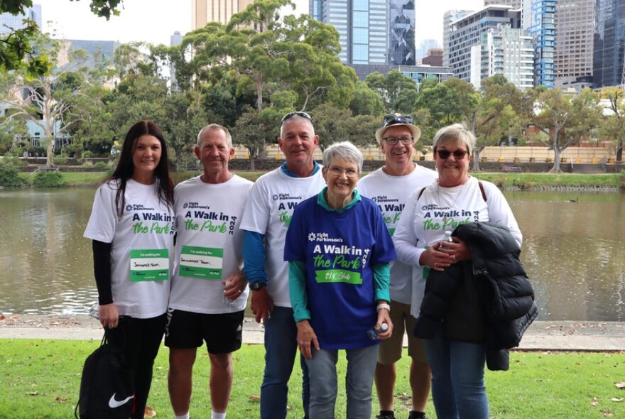 A group of people wearing charity t-shirts, posing in front of the Yarra River.