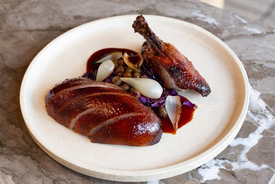 A dish of roasted duck carefully arranged on a white plate.