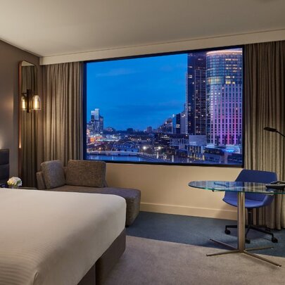 A hotel room with a view of the Melbourne skyline.