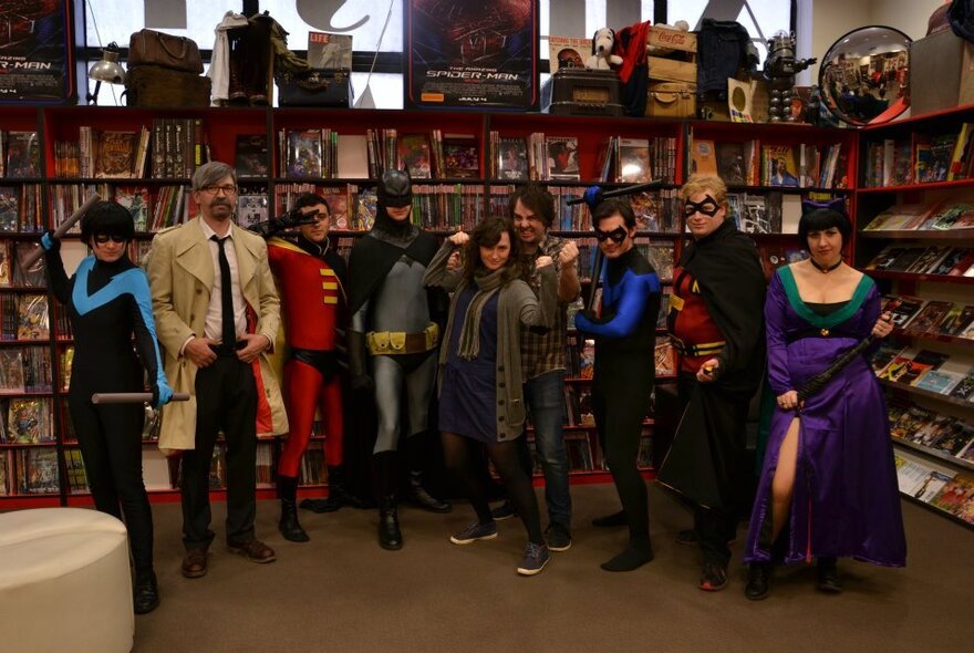 People dressed up as comic book characters in a bookshop setting. 