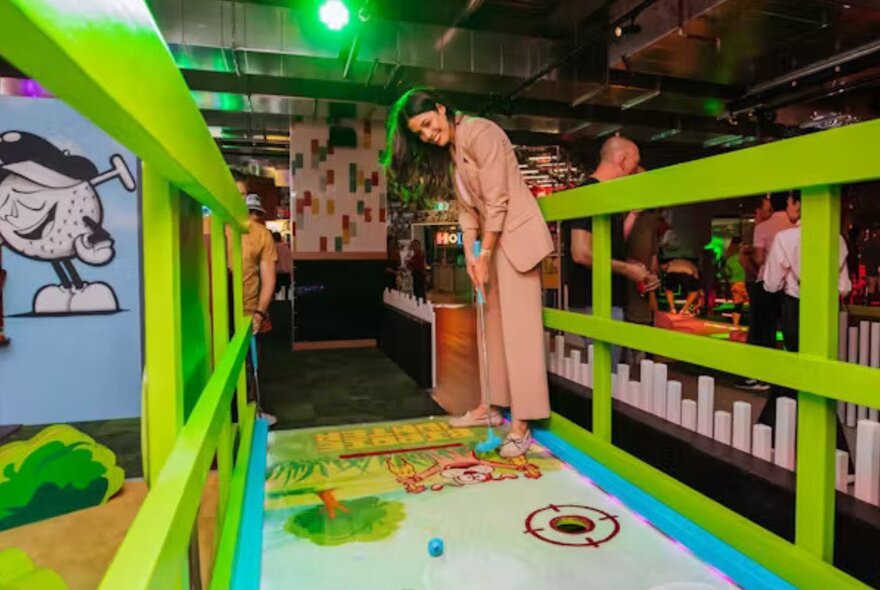 Person playing minigolf in an indoor venue.