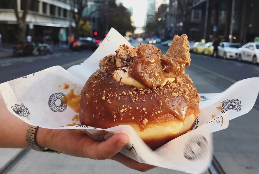 A large glazed doughnut with chunky toppings.