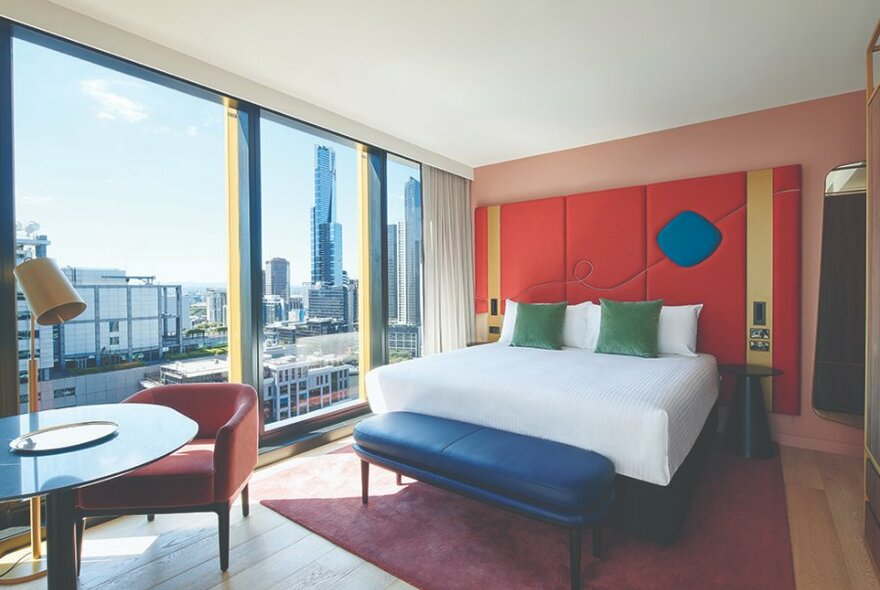 A hotel room with city views and brightly coloured geometric decor.