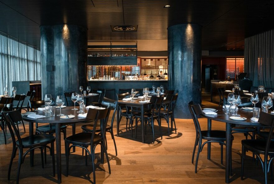 Interior of venue, showing tables and chairs, a central bar area, and soft lighting.