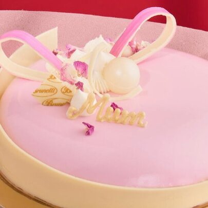 Pink celebration cake with white chocolate ribbon decoration. 