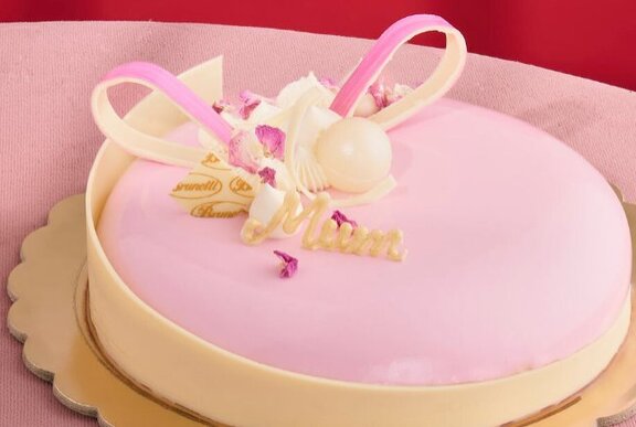 Pink celebration cake with white chocolate ribbon decoration. 