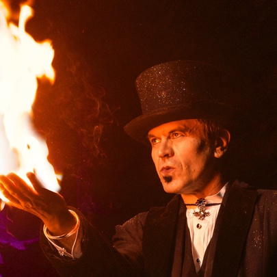 Magician wearing a top hat with flames issuing from his outstretched hand.