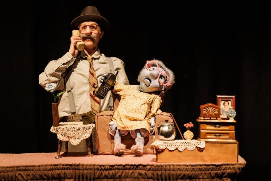 A puppet theatre production taking place on a darkened stage.