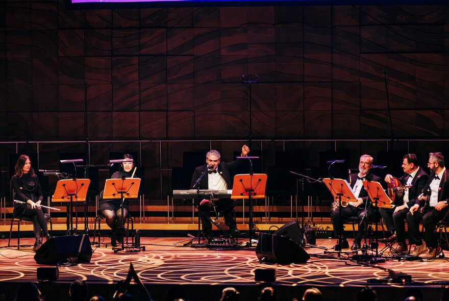 Musicians performing in formal attire on a large stage.