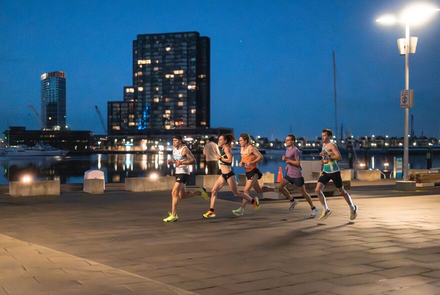 A group of people running in the early hours of the morning, city buildings in the background, as part of the Run Melbourne fun run.