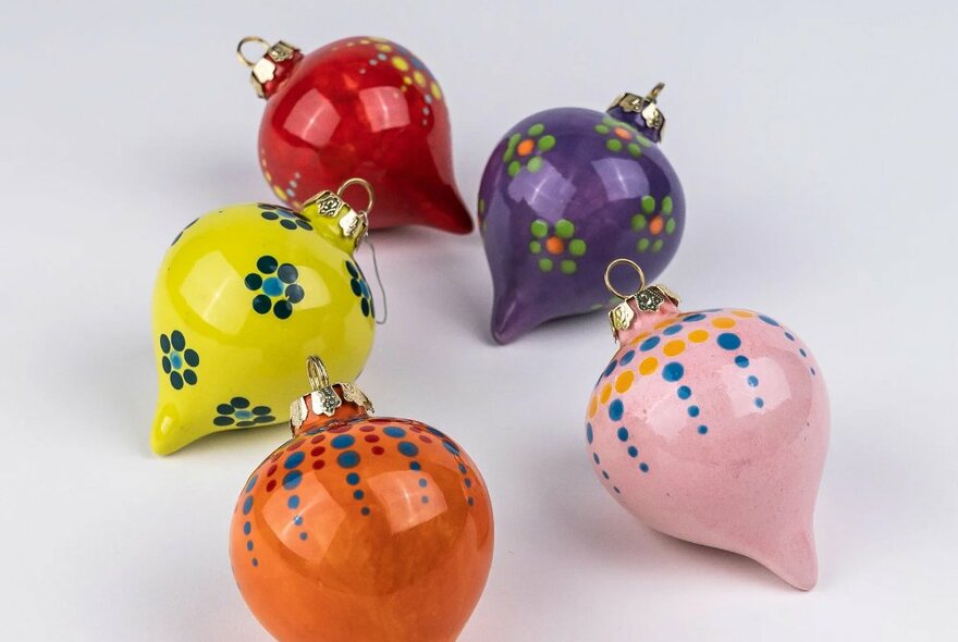 A selection of ceramic painted Christmas baubles in different colours.