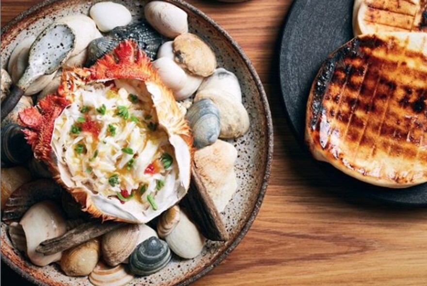 Spanner crab served in its shell on a plate of pebbles.