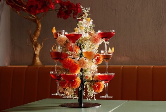 A tabletop tree statue holding different pink cocktails.