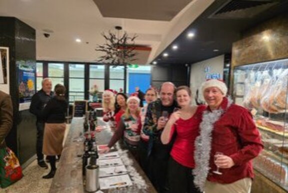 A group of people wearing festive Christmas clothes in a restaurant.