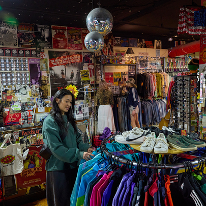 A woman browsing a rack of colourful jackets in a vintage shop with disco balls.