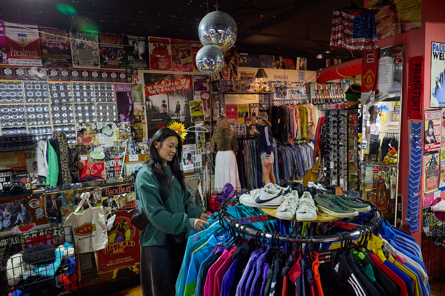 A woman browsing a rack of colourful jackets in a vintage shop with disco balls.