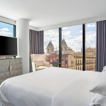 Hotel room at Sheraton Melbourne, with floor to ceiling windows with city views, decorated with simple but classic furnishings.