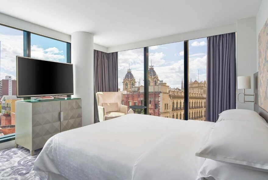 Hotel room at Sheraton Melbourne, with floor to ceiling windows with city views, decorated with simple but classic furnishings.