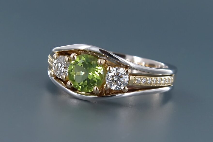 A silver and gold ring with a green gemstone set in its centre.