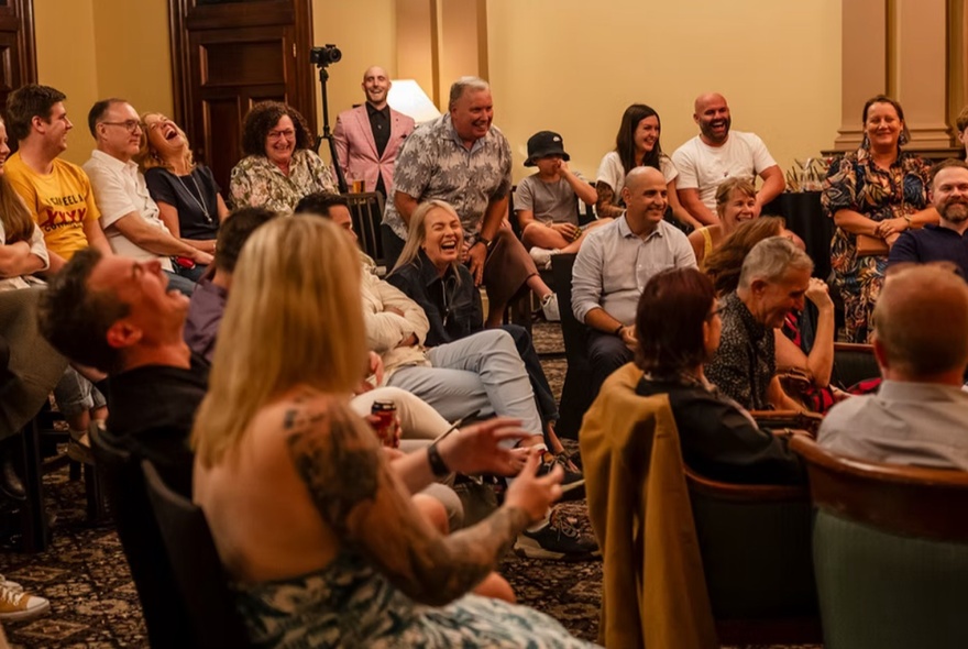 A seated audience in an intimate theatre setting watching a magician perform.