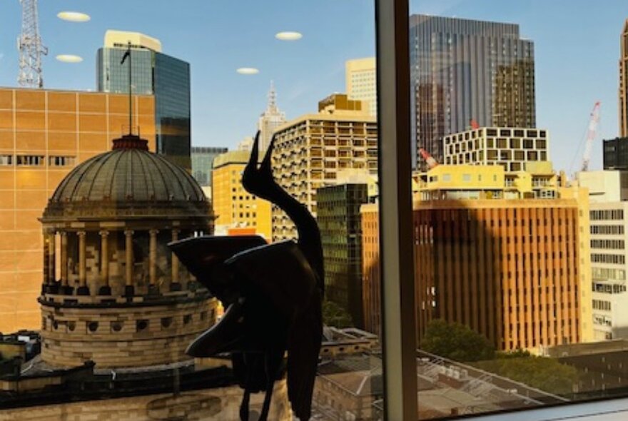 Bird sculpture on a windowledge in front of a view of the Supreme Court dome.