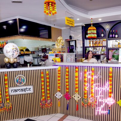 The restaurant counter at an Indian resturarant hung with yellow and red flower garlands.
