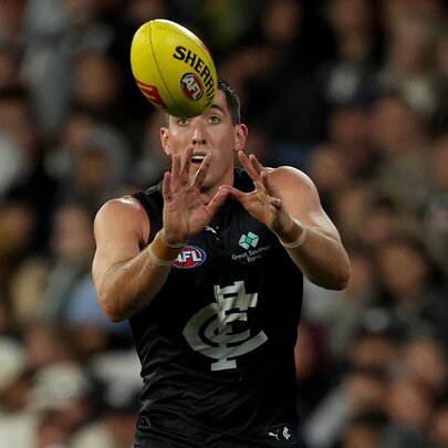 A Carlton AFL football player catching a yellow ball during a match.