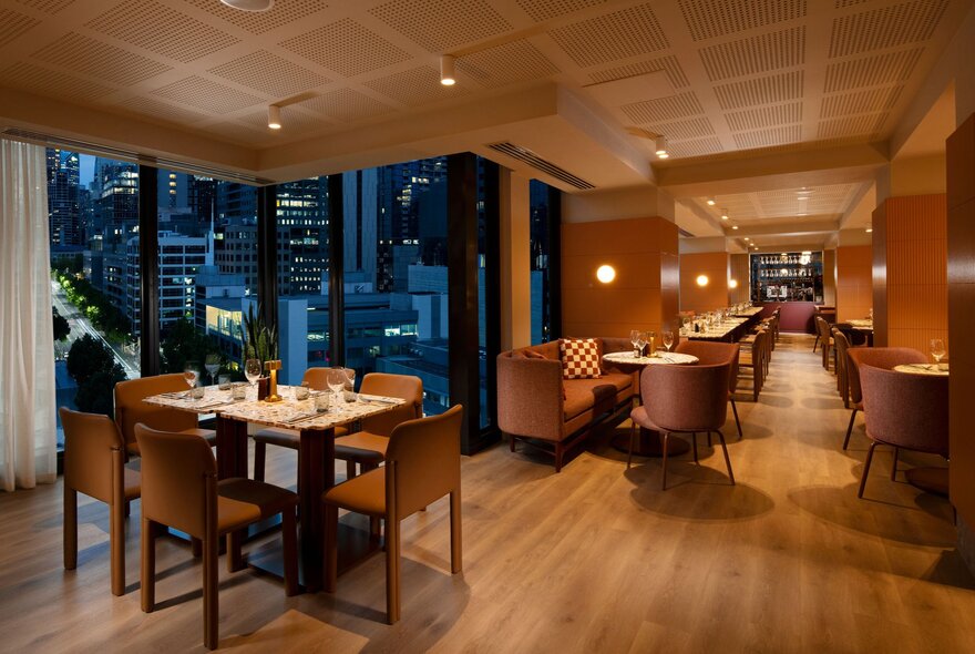 A dining area in a hotel with warm wood tones and ambient lighting. 
