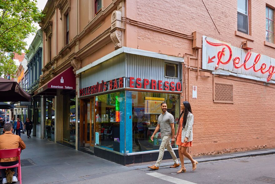 A man and a woman walking around the corner of an old school Italian restaurant.