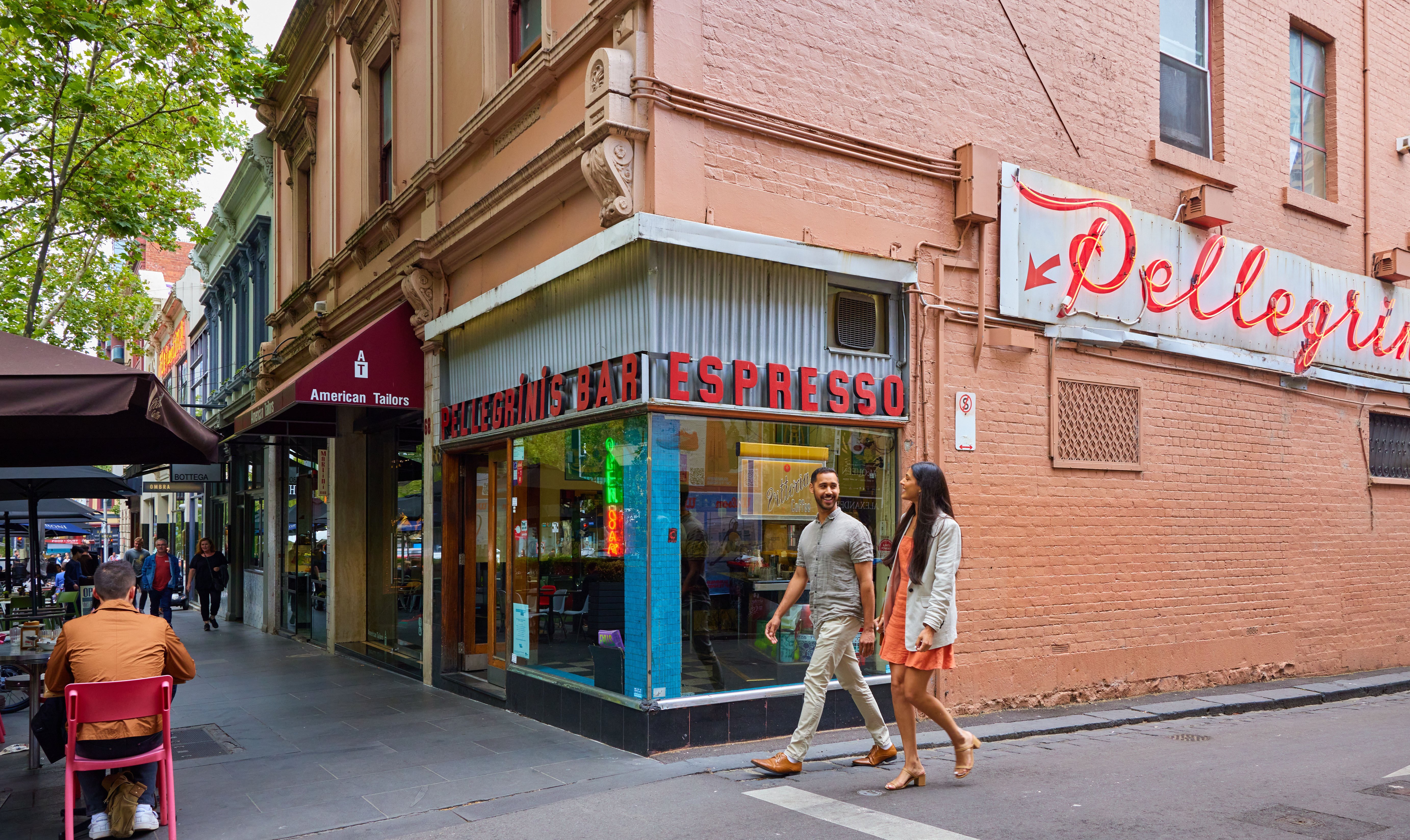 A man and a woman walking around the corner of an old school Italian restaurant.