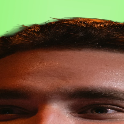 Stretched image of a man's forehead and eyes, with green background.