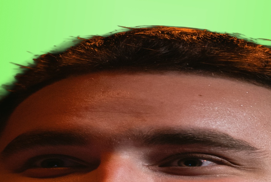 Stretched image of a man's forehead and eyes, with green background.