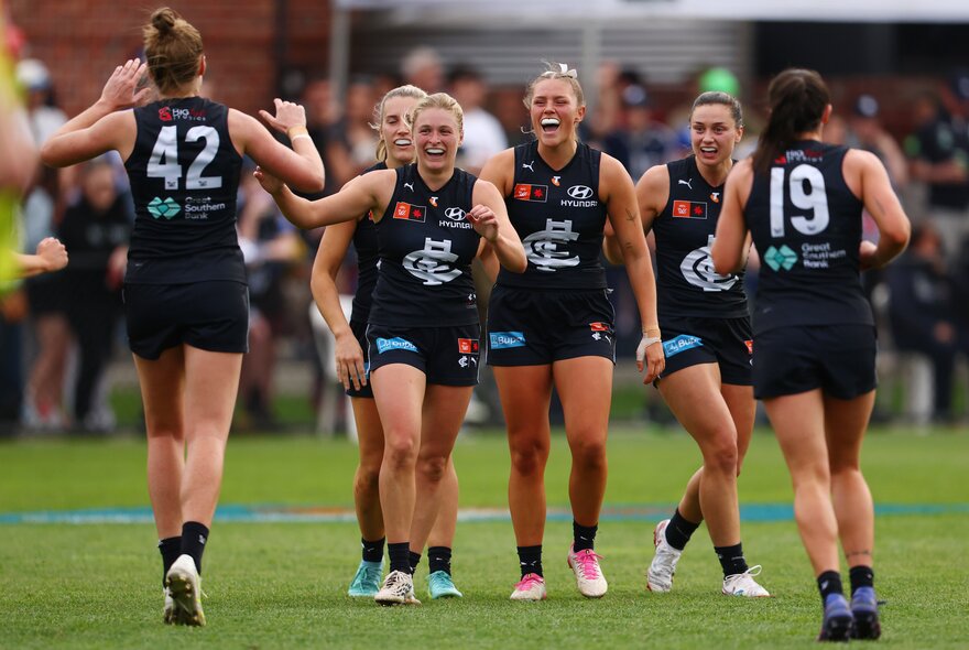 Carlton Blues AFLW players celebrating on the field.