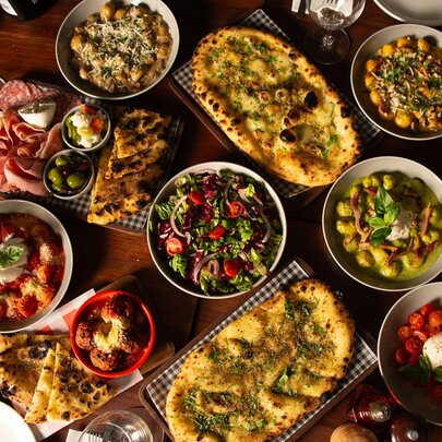 Looking down on a table with a vast array of pizza and salads.