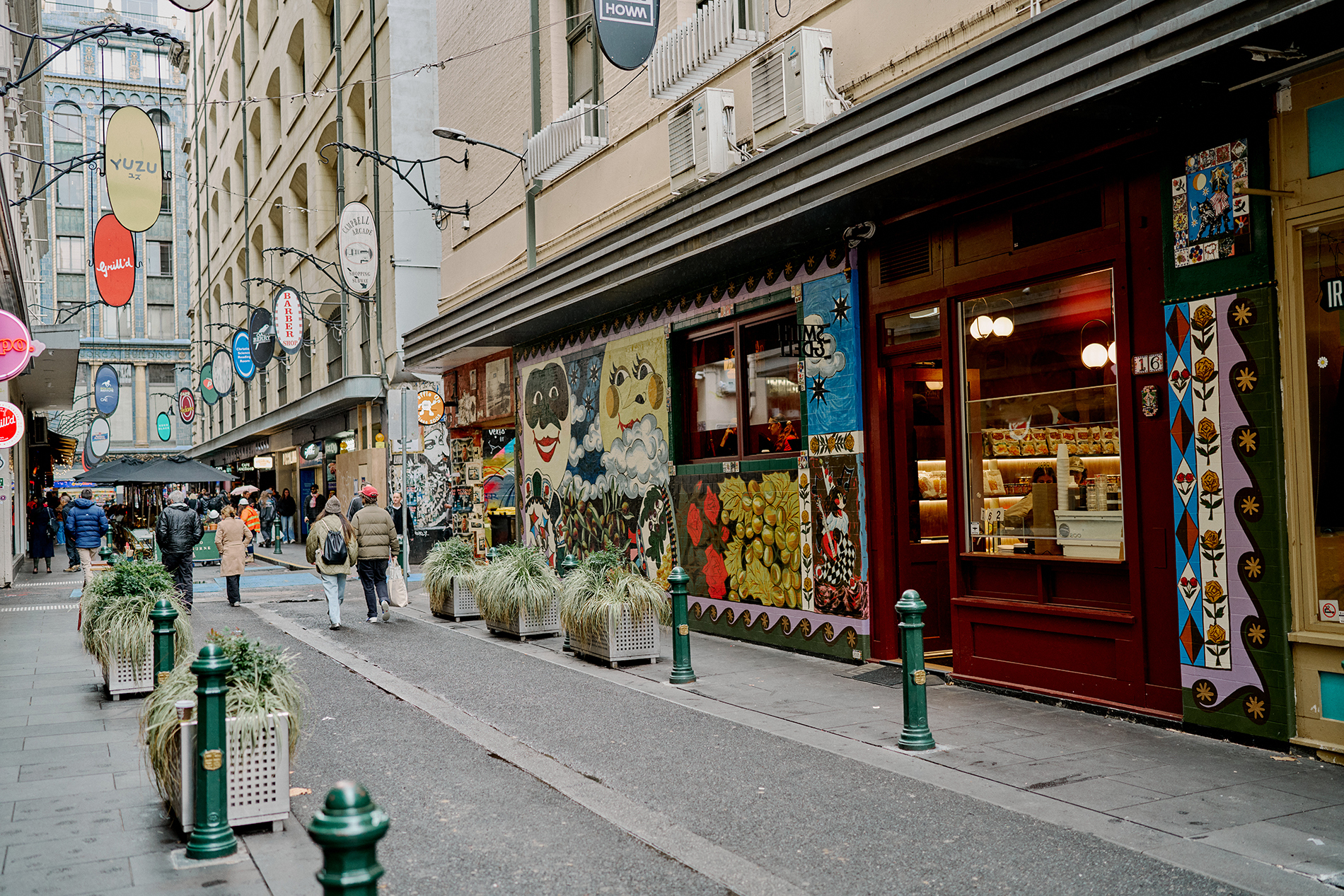 A busy laneway with cafes and colourful signs.