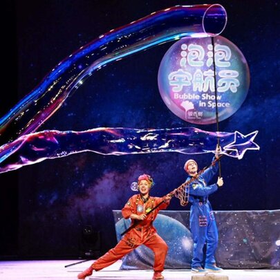Two performers on stage making very long and large bubbles.