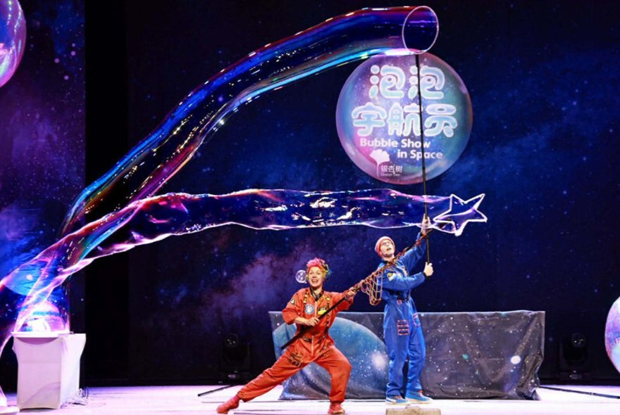 Two performers on stage making very long and large bubbles.